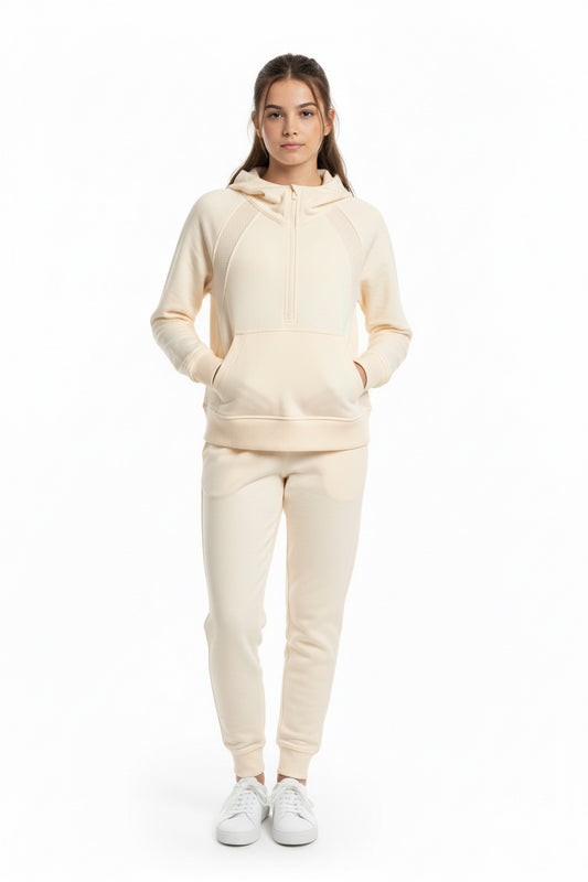 Person wearing a beige hoodie and pants set on a white background