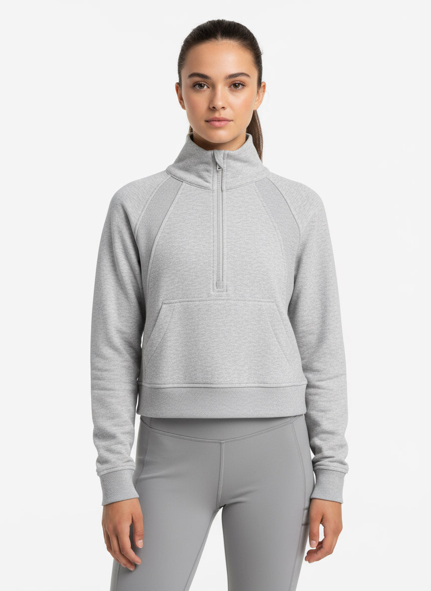 Woman wearing a gray half-zip sweatshirt and pants on a white background