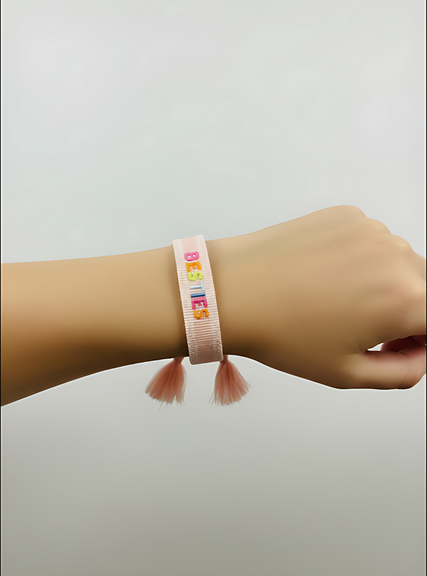 Pink bracelet with colorful beads on a wrist against a light gray background