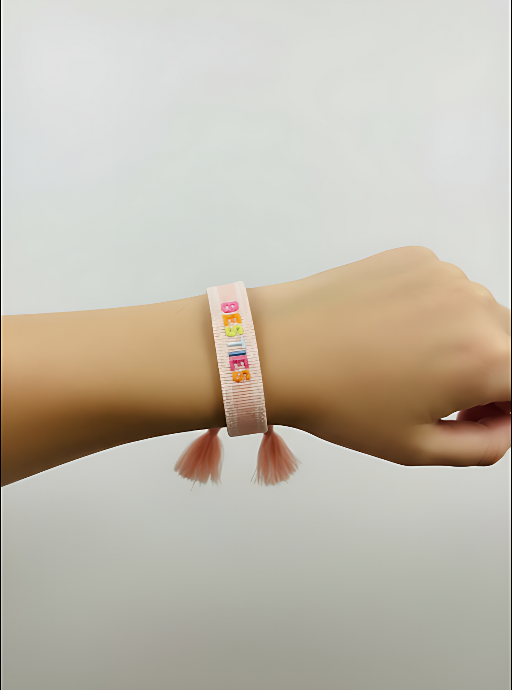 Pink bracelet with colorful beads on a wrist against a light gray background