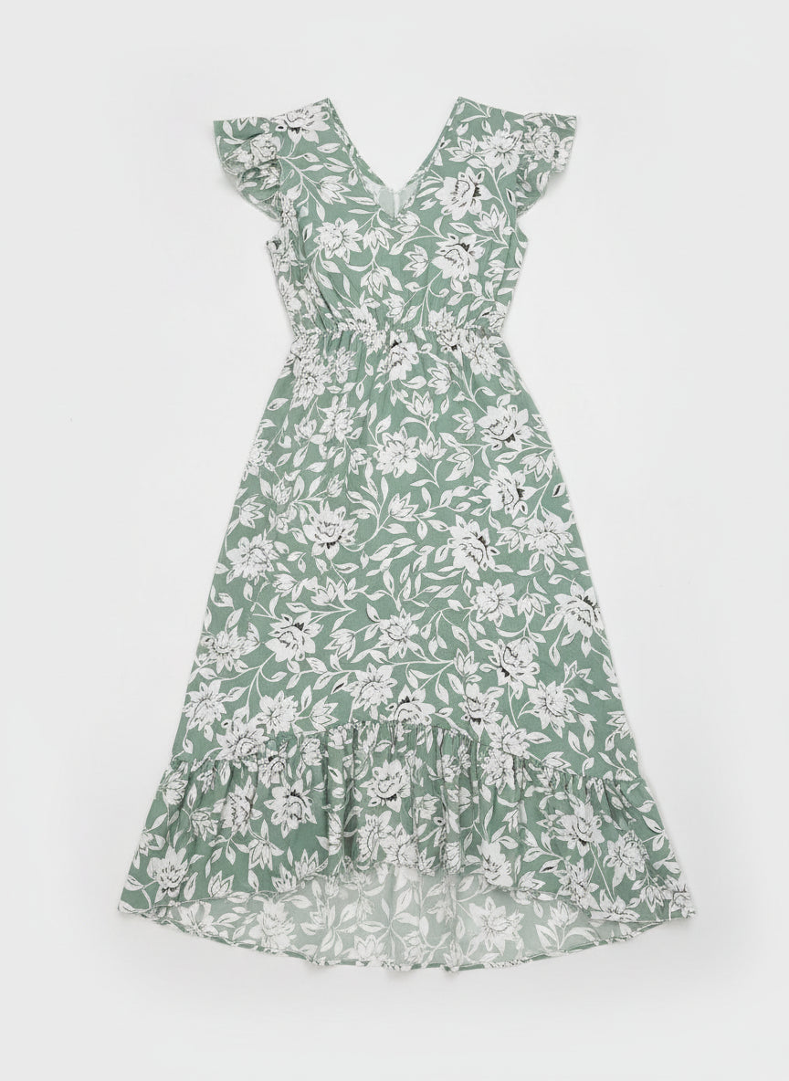 Woman wearing a green floral dress in a modern living room.