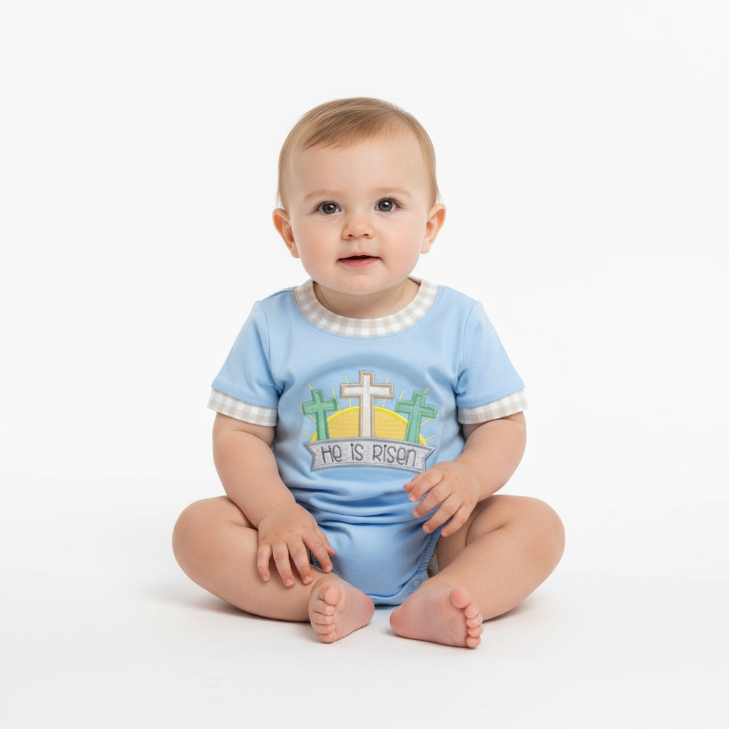 Baby wearing a blue 'He is Risen' shirt with crosses on a white background