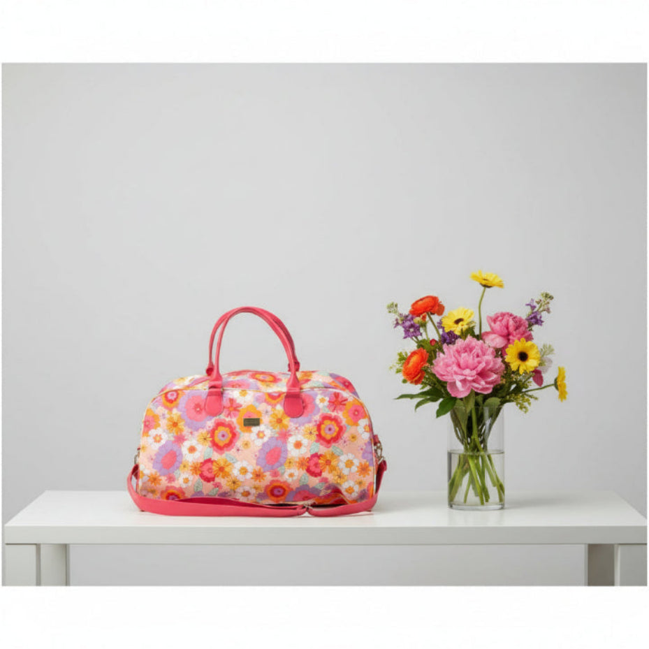 Floral patterned handbag with pink handles and strap on a white background