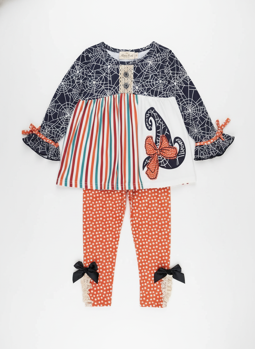 Children's outfit with spider web top, striped dress, and polka dot leggings on a wooden background