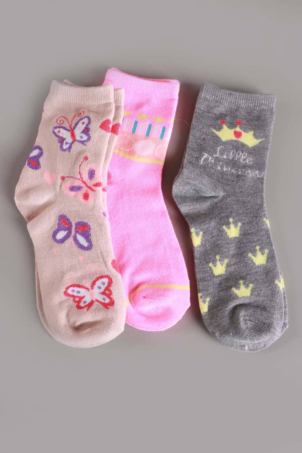 Three pairs of children's socks with butterfly, princess crown, and 'Little Princess' designs on a gray background.